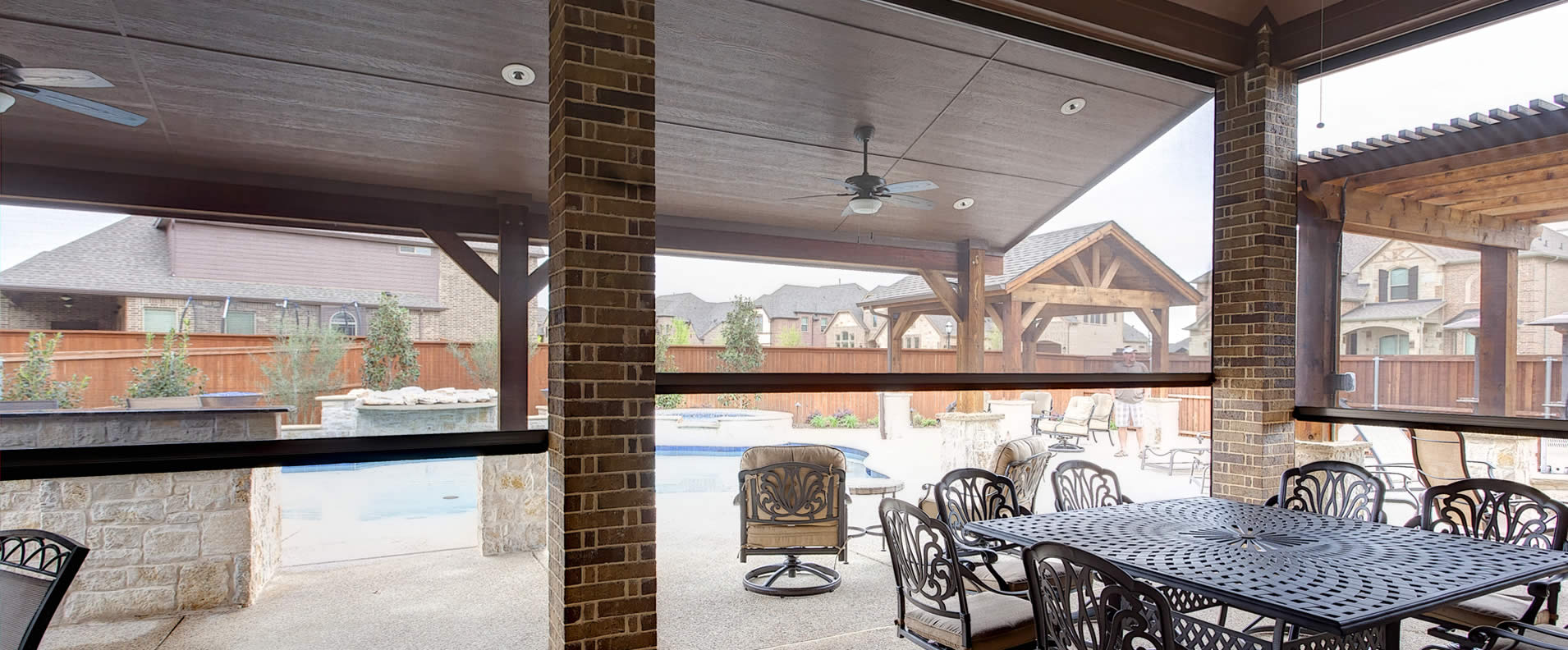 Backyard patio table, chairs, pool with enclosed motorized patio shades used as walls.